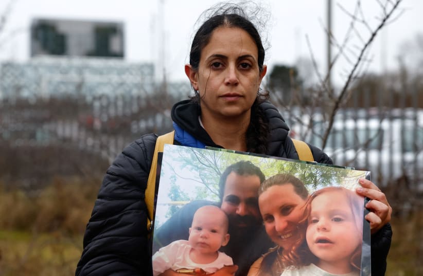  Ofri Bibas Levy, 37, poses with a picture of her family still held hostage after representatives of families of hostages taken by Hamas on October 7 held a press conference, after submitting legal filings to the International Criminal Court. February 14, 2024. (photo credit: REUTERS/PIROSCHKA VAN DE WOUW)