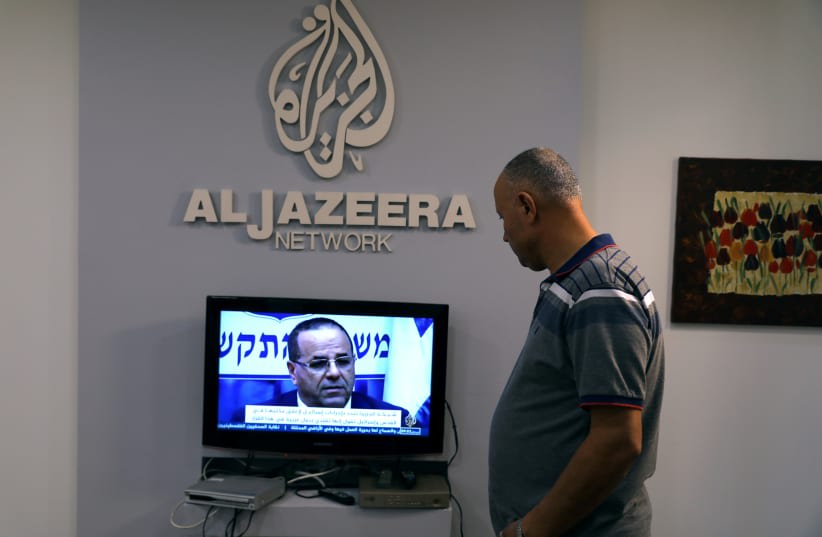  Un empleado trabaja dentro de la oficina de la cadena qatarí Al-Jazeera en Jerusalén (photo credit: AMMAR AWAD/REUTERS)