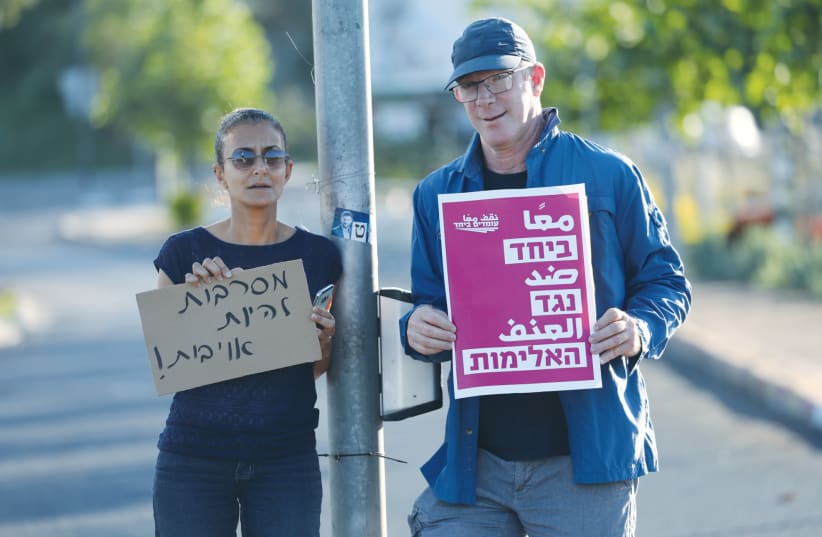  TWO DEMONSTRATORS hold signs at a protest calling for calm and Jewish-Arab coexistence in Lod in 2021, following a night of rioting by Arab residents in the city. The signs read: ‘We refuse to be enemies,’ and ‘Together against violence.’ (photo credit: YOSSI ALONI/FLASH90)