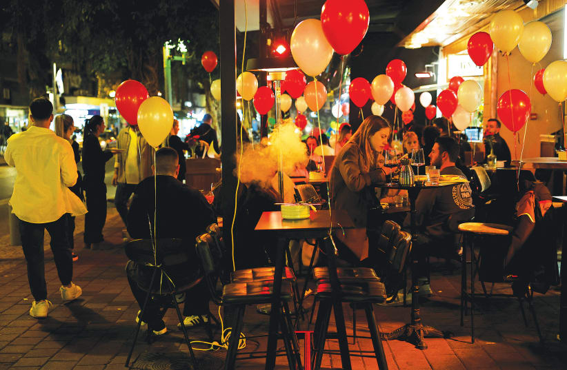  PEOPLE HANG OUT at an outdoor restaurant terrace in Tel Aviv with Valentine’s Day decorations this week. (photo credit: SUSANA VERA/REUTERS)