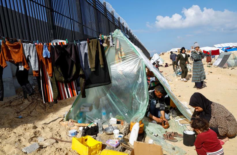  Miembros desplazados de la familia Abu Mustafa, palestinos que huyeron de su casa debido a los ataques israelíes, preparan alimentos mientras se refugian en la frontera con Egipto, en Rafah, en el sur de la Franja de Gaza, el 10 de febrero de 2024. (photo credit: REUTERS/MOHAMMED SALEM)