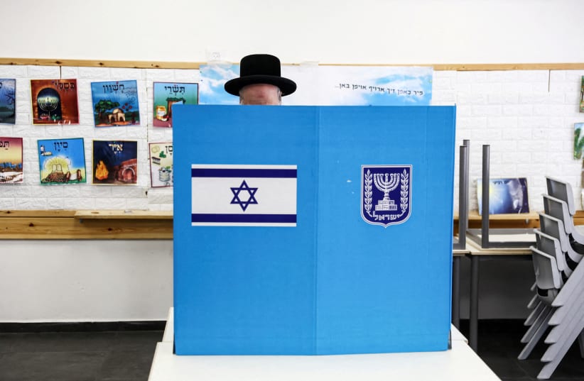  An Ultra-Orthodox Jewish Israeli selects his ballot paper on the day of Israel's general election in a polling station in Jerusalem November 1, 2022. (photo credit: RONEN ZVULUN/REUTERS)