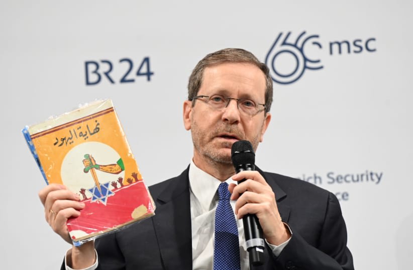  El presidente Isaac Herzog revela un libro antisemita encontrado en Gaza en la Conferencia de Seguridad de Munich, 17 de febrero de 2024 (photo credit: CHAIM TZACH/GPO)
