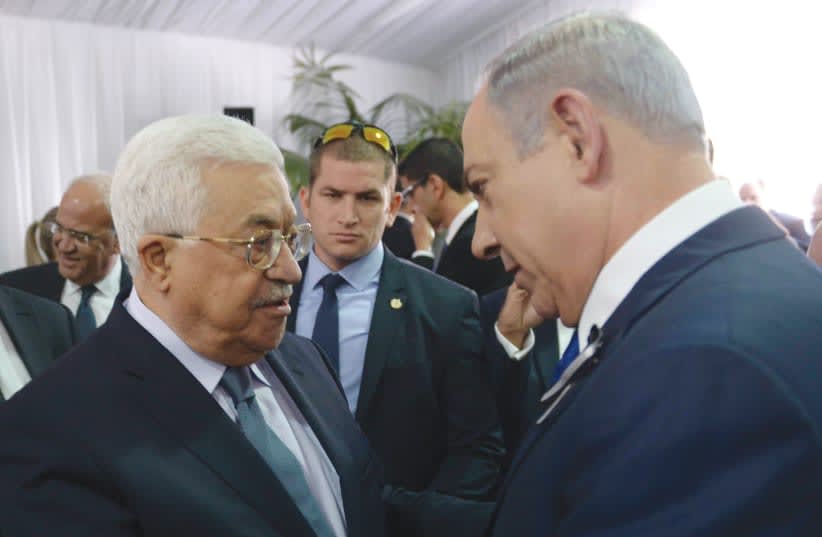  El PRIMER MINISTRO Benjamín Netanyahu y el jefe de la AP, Mahmud Abás, se dan la mano en el funeral de Shimon Peres en el monte Herzl, en Jerusalén, en 2016. (photo credit: AMOS BEN GERSHOM/GPO)