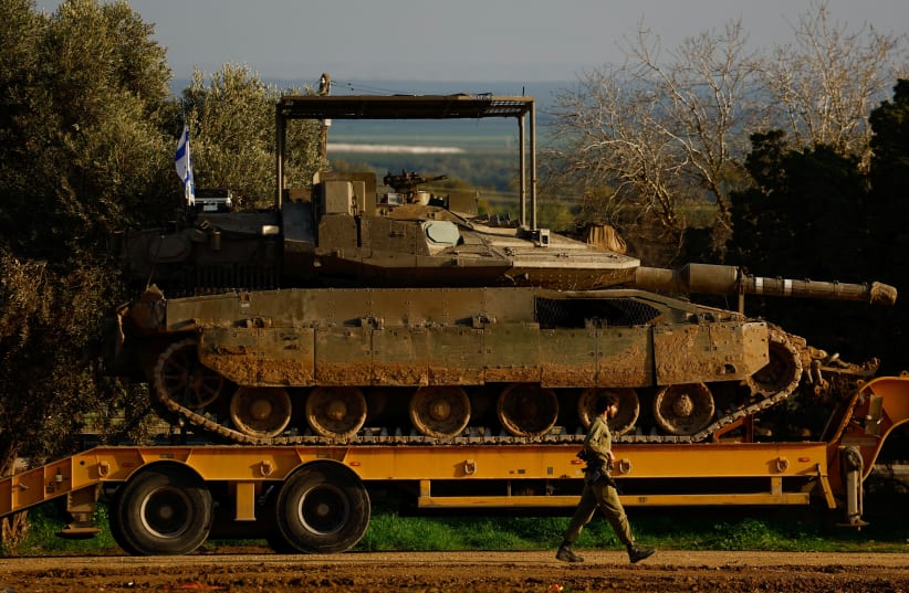  Israeli flags are seen as tanks and armoured personnel carriers wait to be unloaded outside Kibbutz Be'eri, February 18, 2024 (photo credit: REUTERS/SUSANA VERA)