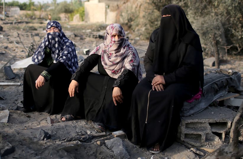  Mujeres palestinas sentadas junto a los escombros de una casa destruida en un ataque aéreo en el sur de la Franja de Gaza 13 de noviembre de 2019 (photo credit: REUTERS/IBRAHEEM ABU MUSTAFA)