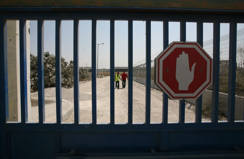  Palestinians walk beside a closed gate of the main commercial crossing of Karni linking the Gaza Strip and Israel,  September 15, 2008. (photo credit: Wissam Nassar/Flash90.)