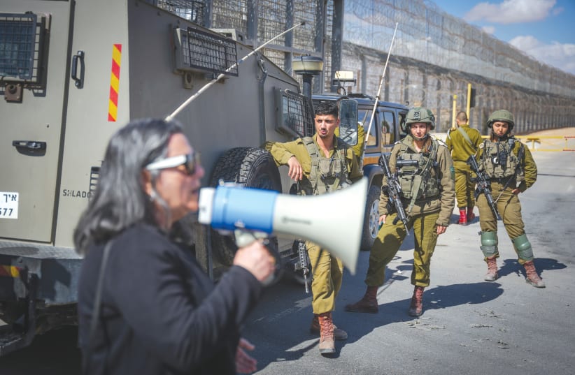  IDF SOLDIERS look on as an Israeli woman leads a protest against the transfer of aid to the Gaza Strip, at the Nitzana Border Crossing, last week.  (photo credit: ERIK MARMOR/FLASH90)