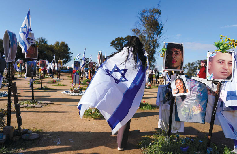  A tourist from Canada walks with an Israeli flag as she visits the site of the Supernova music festival in Re’im. (Illustrative photo) (photo credit: ALEXANDRE MENEGHINI/REUTERS)