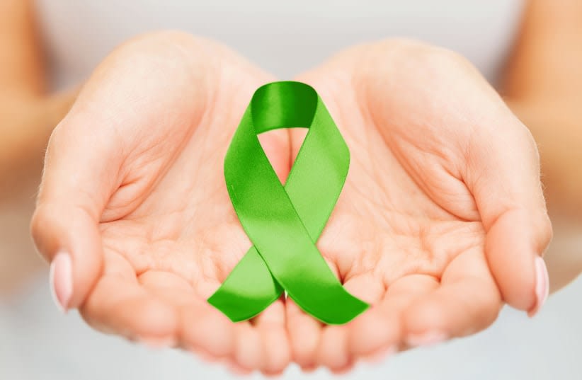  Manos sosteniendo un lazo verde de concienciación sobre el trasplante de órganos (ilustrativo). (photo credit: INGIMAGE)