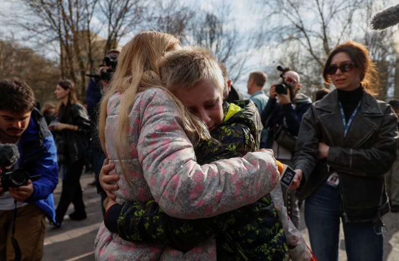  Iryna abraza a su hijo Bohdan, de 13 años, quien fue a un campamento de verano organizado por Rusia desde territorios no controlados por el gobierno y luego fue llevado a Rusia. Este regresó a través de la frontera entre Ucrania y Bielorrusia en Kyiv, Ucrania, el 8 de abril de 2023. (photo credit: REUTERS/VALENTYN OGIRENKO)