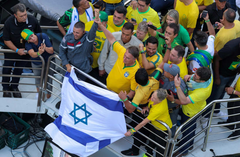  El expresidente de Brasil Jair Bolsonaro reacciona junto a una bandera israelí durante una protesta en la que llamó a sus partidarios a reunirse en la Avenida Paulista, mientras la policía lo investiga a él y a su gabinete por supuestamente planear un golpe de Estado tras las elecciones de 2022, en (photo credit: REUTERS/Carla Carniel)