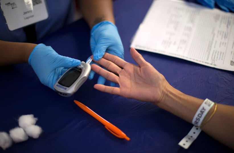  Una persona recibe una prueba de diabetes durante la clínica médica gratuita Care Harbor LA en Los Ángeles, California (photo credit: MARIO ANZUONI/REUTERS)