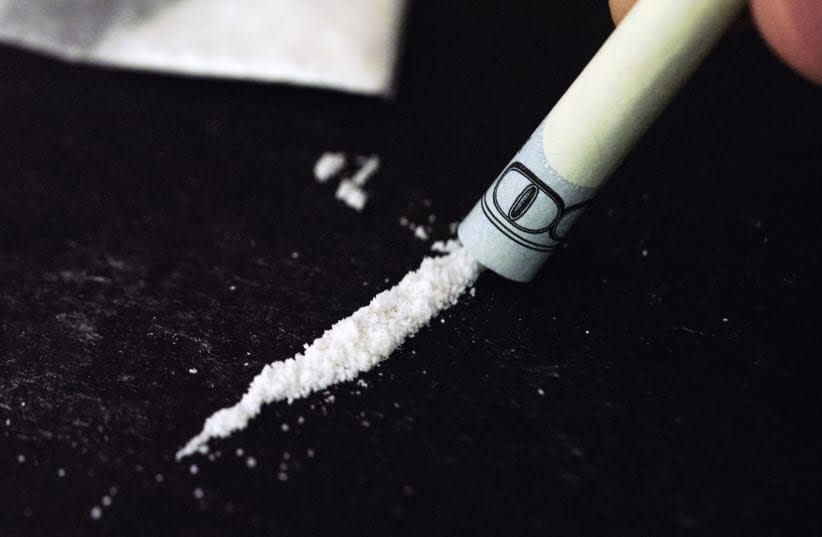  Se ve una raya de cocaína inhalada a través de un dólar enrollado. (photo credit: DANIEL FOSTER/FLICKR)