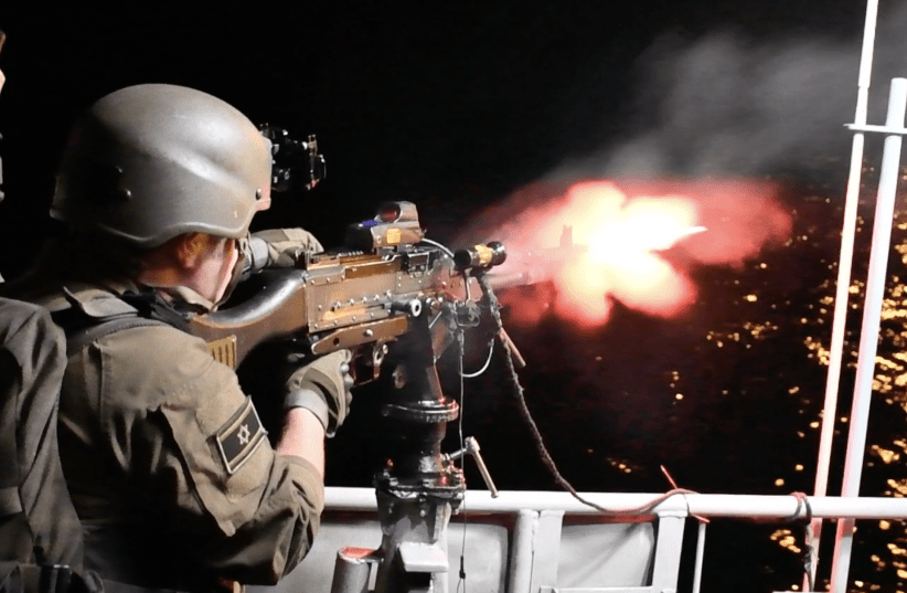  A NAVAL soldier fires his machine gun on the starboard side of a patrol boat during a drill off the coast.  (photo credit: SETH J. FRANTZMAN)