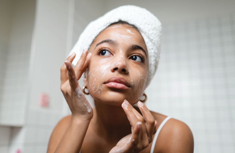  A woman is seen cleaning her face with facial cleanser. (photo credit: Ron Lach/Pexels)