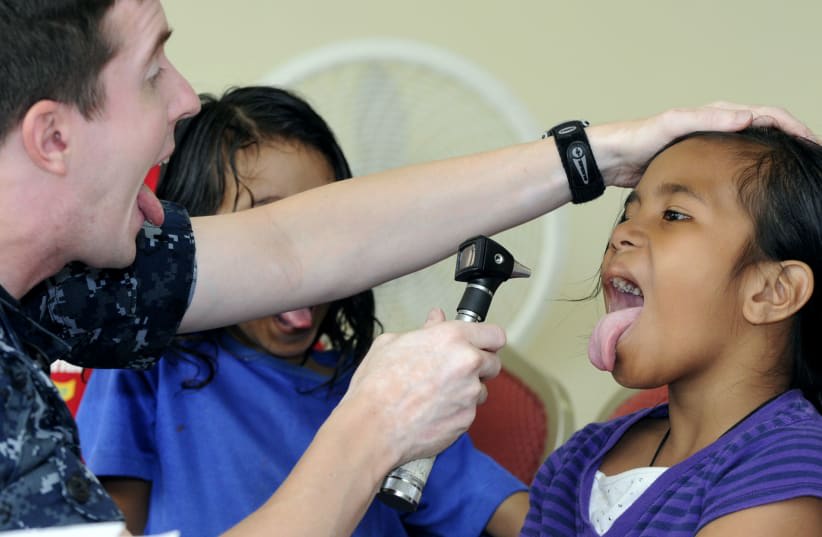  Un médico de la Marina estadounidense revisa las amígdalas de un paciente durante un proyecto de acción cívica médica de la Alianza del Pacífico 2010. (photo credit: PUBLIC DOMAIN)