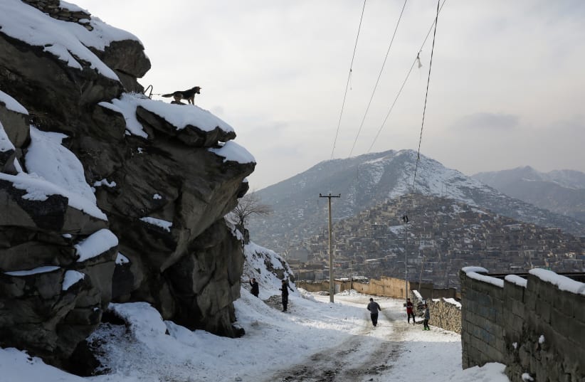  People walk on a snow-covered street on the so-called 'TV mountain' in Kabul, Afghanistan, January 30, 2023. (photo credit:  REUTERS/ALI KHARA)