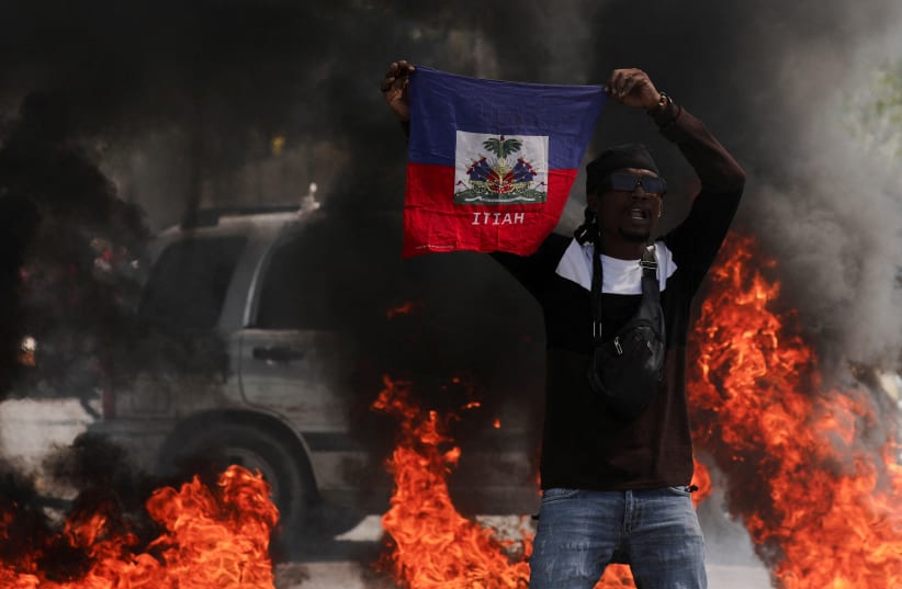  A demonstrator holds up a Haitian flag during a protest against Prime Minister Ariel Henry's government and insecurity, in Port-au-Prince, Haiti March 1, 2024. (photo credit: REUTERS)