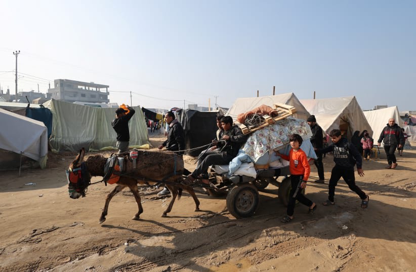  Varias personas transportan sus pertenencias en un carro tirado por animales mientras los palestinos desplazados, que huyeron de sus hogares debido a los ataques israelíes, se refugian en un campamento de tiendas de campaña en Rafah, sur de la Franja de Gaza, 1 de enero de 2024. (photo credit: REUTERS/IBRAHEEM ABU MUSTAFA)