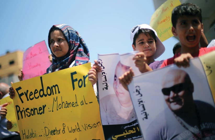  PALESTINIANS PROTEST in Gaza City, in 2016, in solidarity with Mohammad El Halabi, World Vision’s manager of operations in Gaza. He was arrested for helping Hamas divert $50 million provided by the Australian government, and a few years later, was convicted and sentenced.  (photo credit: MOHAMMED SALEM/REUTERS)
