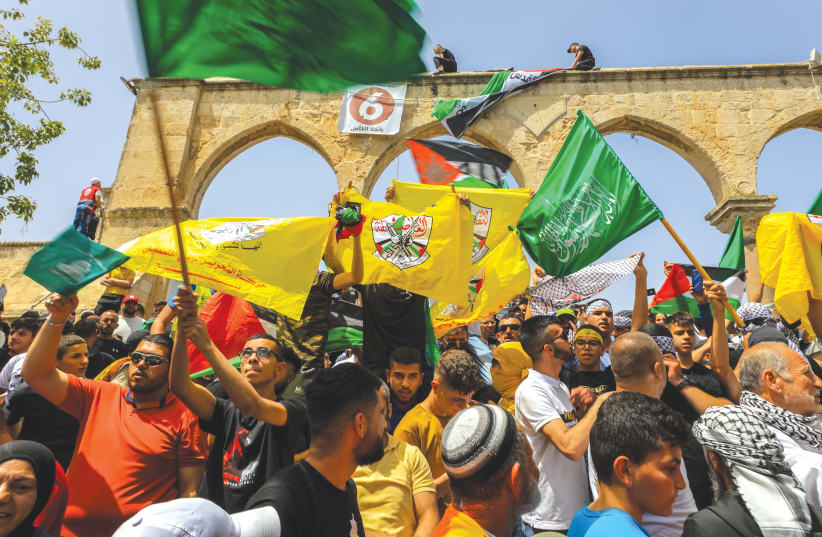 PALESTINIANS SHOUT slogans and wave flags, including of Hamas, depicting Israel as part of Palestine at al-Aqsa compound on the Temple Mount during Ramadan, last year. (photo credit: JAMAL AWAD/FLASH90)