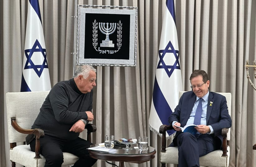  PRESIDENT ISAAC HERZOG smiles as he peruses Moshe Mizrahi’s memoir. (photo credit: OFFICE OF THE PRESIDENT)