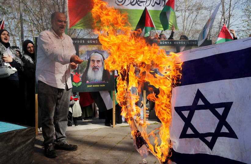  Manifestantes propalestinos prenden fuego a una bandera israelí durante una concentración para conmemorar el Día de al-Quds (Día de Jerusalén) anual, durante el mes sagrado del Ramadán en Estambul, Turquía, el 14 de abril de 2023. (photo credit: REUTERS/DILARA SENKAYA)