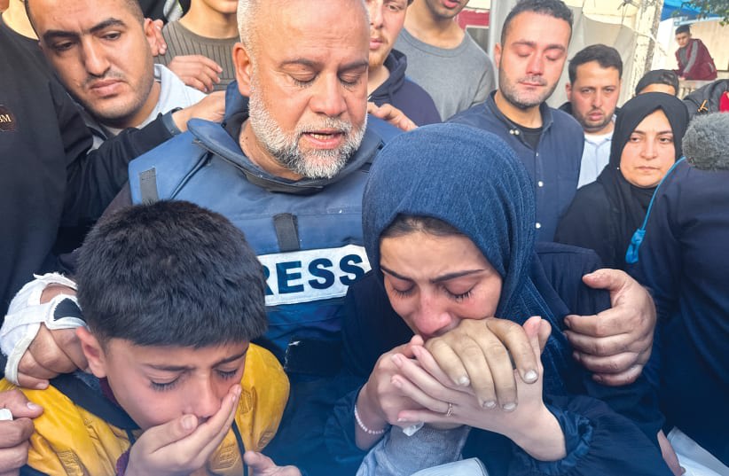  El jefe de la oficina de Al Jazeera, Wael Al-Dahdouh, abraza a su hija y a su hijo mientras asisten al funeral, el 7 de enero, de su hijo, el periodista Hamza Al-Dahdouh, muerto en un ataque israelí en Rafah, en el sur de la Franja de Gaza. (photo credit: (Mohammed Salem/Reuters))
