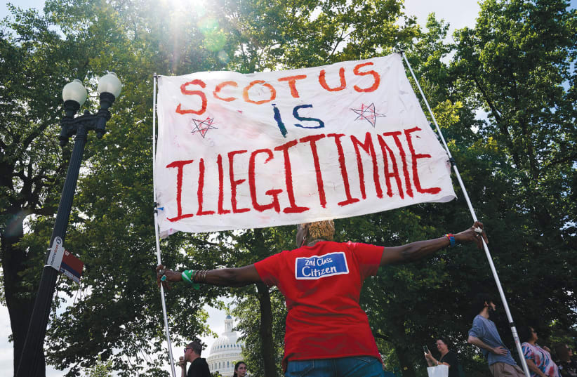 UNA activista por el derecho al aborto denuncia que el Tribunal Supremo de EE.UU. es "ilegítimo", en una protesta en Washington, en junio, en el primer aniversario de la sentencia judicial que anuló el caso Roe contra Wade. (photo credit: Elizabeth Frantz/Reuters)