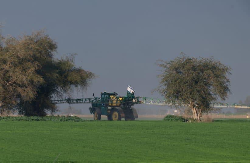  Un vehículo agrícola con bandera israelí trabaja en un campo cerca de la frontera con el sur de Gaza, en medio del conflicto en curso entre Israel y el grupo islamista palestino Hamás, Israel, 12 de febrero de 2024. (photo credit: AMIR COHEN/REUTERS)