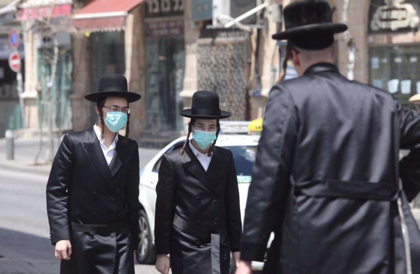  Hombres ultraortodoxos con máscaras caminan por el barrio de Mea Shearim, Jerusalén, 12 de abril de 2020. (photo credit: MARC ISRAEL SELLEM/THE JERUSALEM POST)