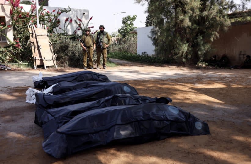  Soldados israelíes custodian los cuerpos de las víctimas de un ataque tras una infiltración masiva de hombres armados de Hamás desde la Franja de Gaza, en el kibutz Kfar Aza, en el sur de Israel, el 10 de octubre de 2023. (photo credit: RONEN ZVULUN/REUTERS)