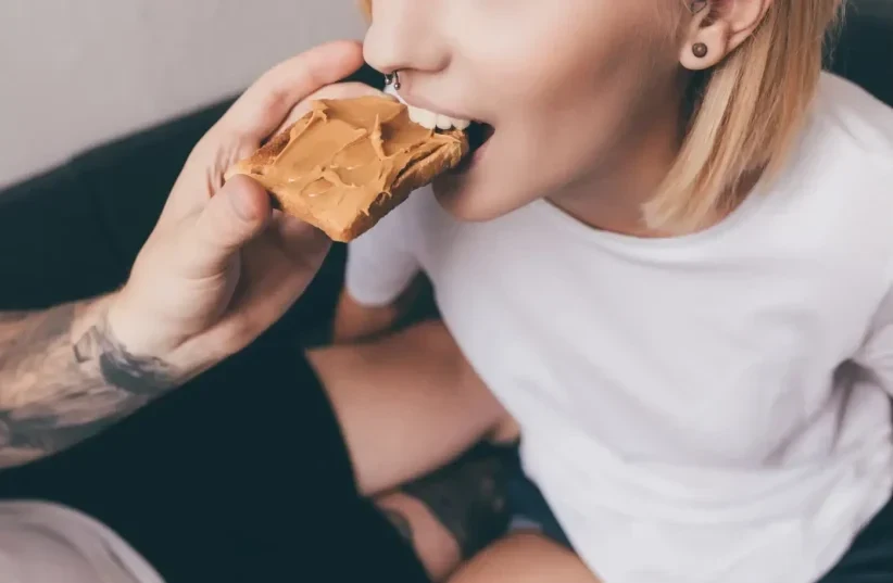  Mujer joven comiendo mantequilla de cacahuete (photo credit: SHUTTERSTOCK)