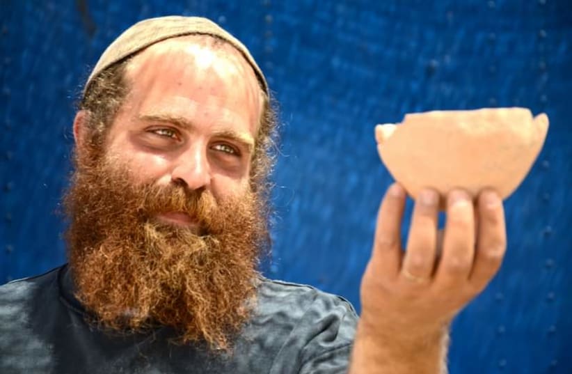  Benjamin Storchan sostiene los hallazgos de la excavación. (photo credit: SKYVIEW, COURTESY OF THE ISRAEL ANTIQUITIES AUTHORITY, YULI SCHWARTZ/IAA)