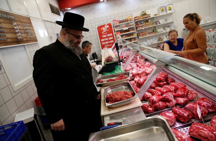  Kosher inspector Aaron Wulkan examines display refrigerators containing meat in a food store to ensure that the food is stored and prepared according to Jewish regulations and customs in Bat Yam, Israel, October 31, 2016. (photo credit: BAZ RATNER/REUTERS)