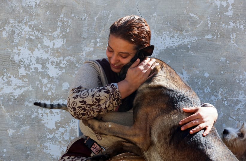  Una mujer tunecina, Houda Bouchahda, acaricia a un perro en una casa convertida en refugio donde, según ella, cuida ella sola de cientos de gatos heridos y docenas de perros, en Hammamet, Túnez 7 de marzo de 2024. (photo credit: REUTERS/JIHED ABIDELLAOUI)