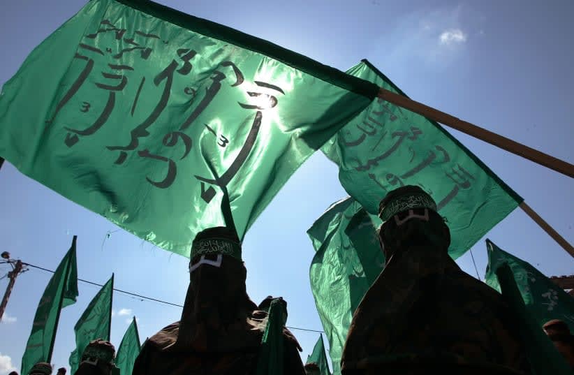  Hombres enmascarados de Hamás ondean banderas durante la marcha en el campo de refugiados de Jabalya, en el norte de la Franja de Gaza, el 4 de octubre de 2002. (photo credit: REUTERS/AHMED JADALLAH)