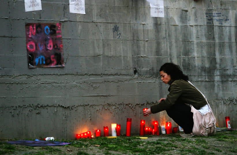  Una mujer enciende una vela en un monumento en memoria de las víctimas de los atentados del 11 de marzo, en el mismo lugar donde hace dos años se produjo un atentado en la estación de Atocha de Madrid, el 11 de marzo de 2006. (photo credit: REUTERS)
