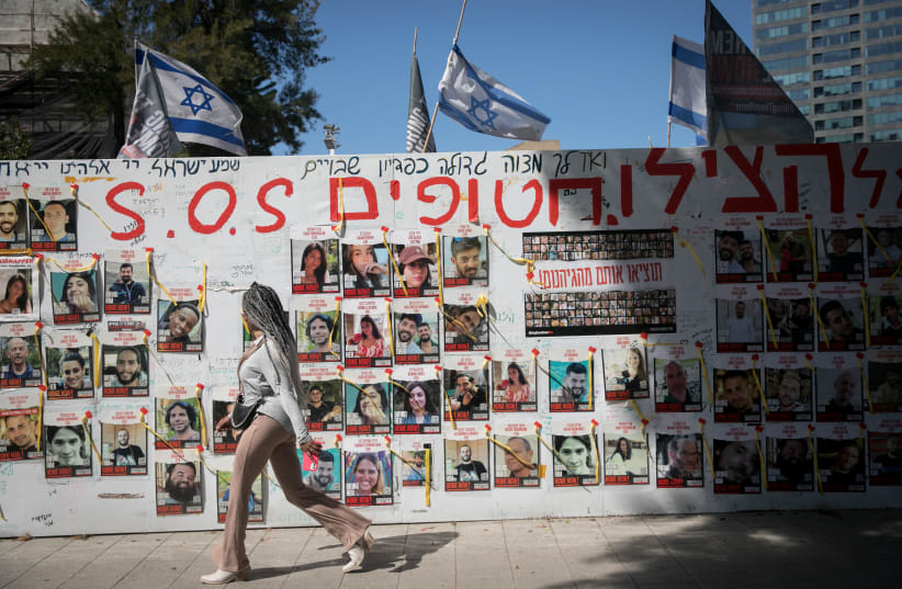  People walk by pphotographs of  Israelis still held hostage by Hamas terrorists in Gaza, at "Hostage Square" in Tel Aviv. March 10, 2024.  (photo credit: MIRIAM ALSTER/FLASH90)