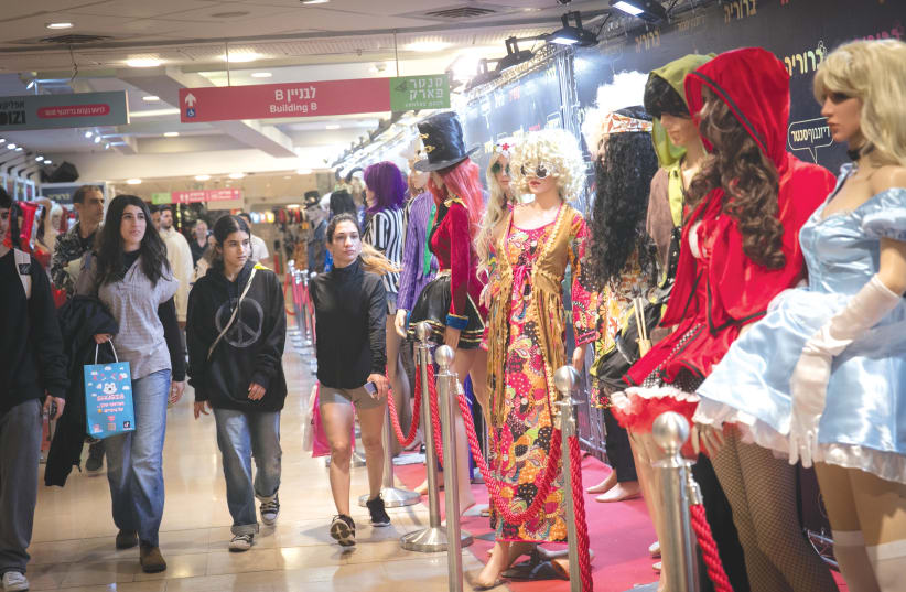  SHOPPERS LOOK at costumes on display at a shop in Tel Aviv, ahead of Purim. It isn’t the time for elaborate gatherings, parties or luxury vacations. Still, we can celebrate our redemptions of the past with the hope for redemption in the near future, says the writer.  (photo credit: MIRIAM ALSTER/FLASH90)