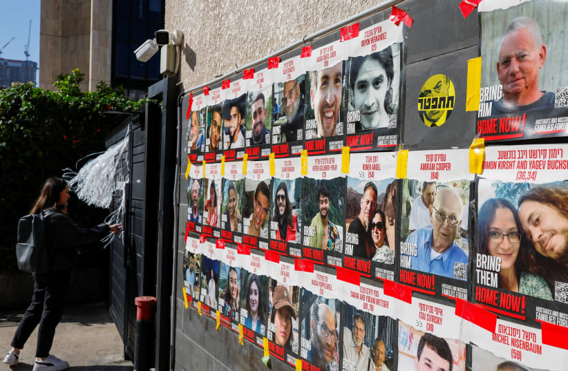  A woman stands next to posters with photos of hostages kidnapped in the deadly October 7 attack on Israel by the Palestinian Islamist group Hamas from Gaza, in Tel Aviv, Israel March 20, 2024.  (photo credit: CARLOS GARCIA RAWLINS/REUTERS)
