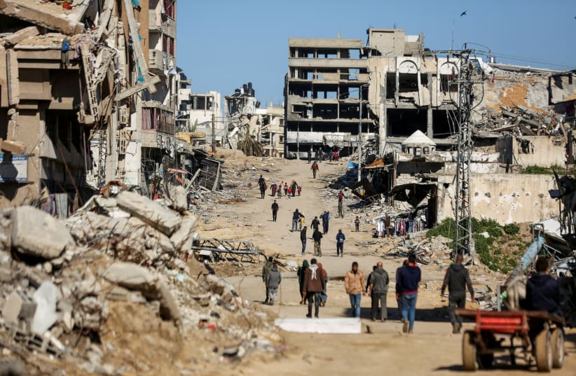  Palestinians walk past the ruins of houses destroyed in Gaza City, March 20, 2024 (photo credit: REUTERS/DAWOUD ABU ALKAS)