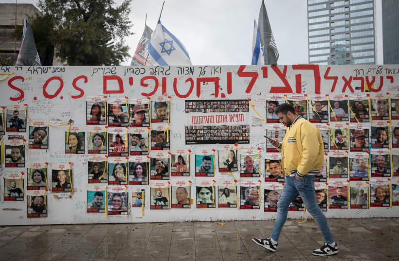  People walk by photographs of Israelis still held hostage by Hamas terrorists in Gaza, in Tel Aviv. March 19, 2024 (photo credit: MIRIAM ALSTER/FLASH90)