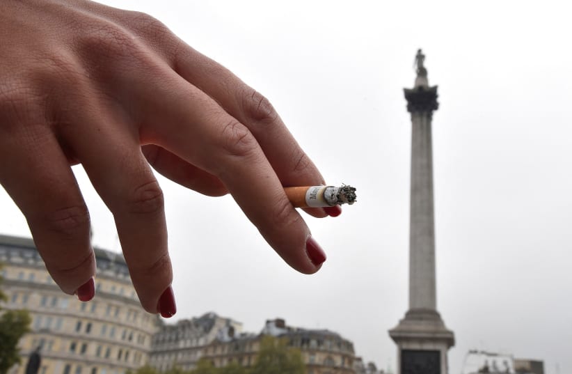  A woman holds her cigarette as she smokes in Trafalgar Square in central London October 15, 2014.  (photo credit: TOBY MELVILLE/REUTERS)