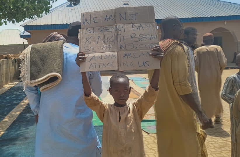  Un niño sostiene una pancarta para protestar contra, lo que un profesor, un concejal local y los padres dijeron, el secuestro de cientos de alumnos de la escuela por hombres armados después de la oración del viernes en Kaduna, Nigeria 8 de marzo 2024. (photo credit: REUTERS/STRINGER/FILE PHOTO)