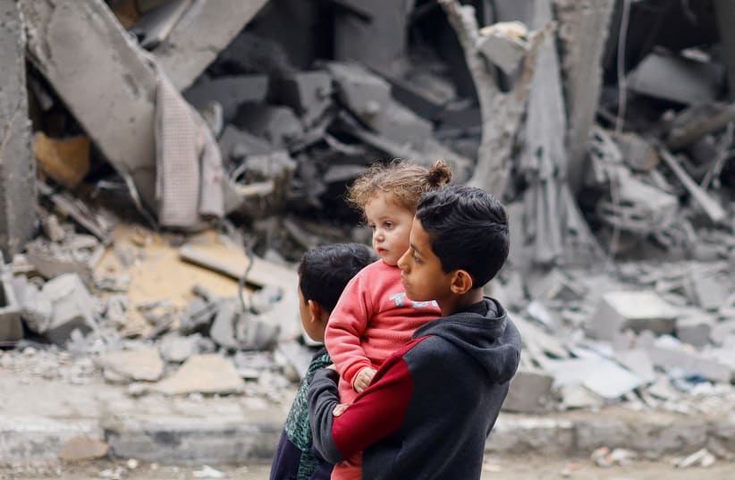  Niños palestinos reaccionan cerca del lugar de un ataque israelí contra una casa, en medio del actual conflicto entre Israel y el grupo terrorista palestino Hamás, en Rafah, en el sur de la Franja de Gaza, 24 de marzo de 2924. (photo credit: (Mohammed Salem/Reuters))