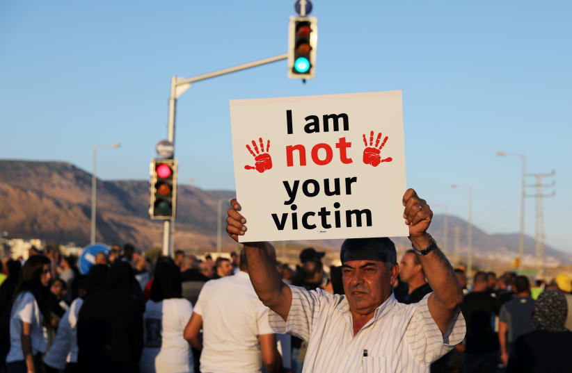 Un hombre sostiene una pancarta durante una protesta contra lo que los ciudadanos árabes israelíes afirman que es la inacción de la policía israelí ante los crímenes violentos en sus pueblos, en Majd al-Krum, norte de Israel 3 de octubre de 2019. (photo credit: AMMAR AWAD/REUTERS)