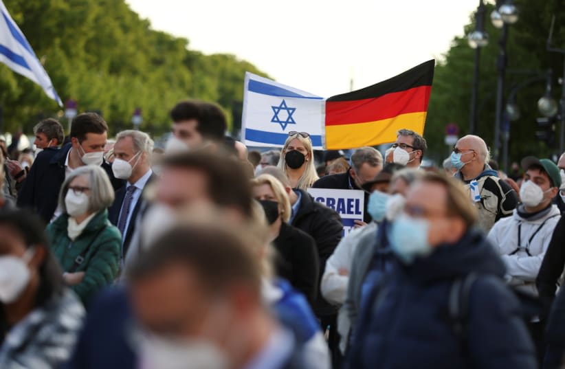  Varias personas portan una bandera israelí y otra alemana durante una concentración en solidaridad con Israel y contra el antisemitismo, frente a la Puerta de Brandeburgo en Berlín, Alemania, 20 de mayo de 2021. (photo credit: REUTERS/CHRISTIAN MANG)