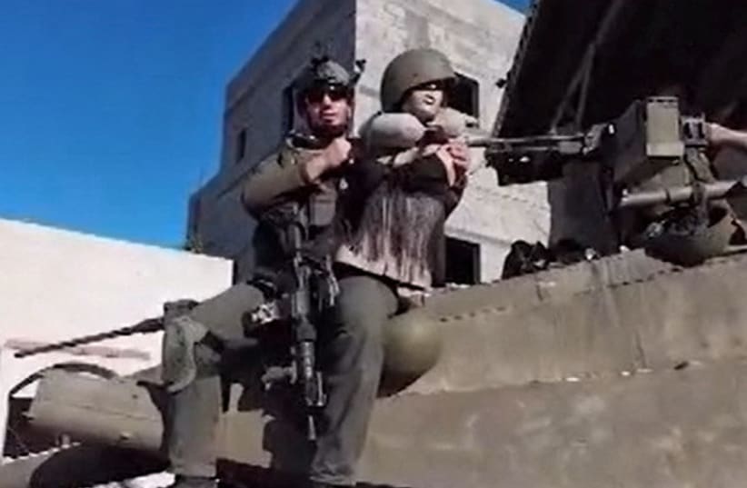  An Israeli soldier sits on top of a tank holding a female mannequin in a screengrab of a video (photo credit: SCREENSHOT/IDF SPOKESPERSON'S UNIT)